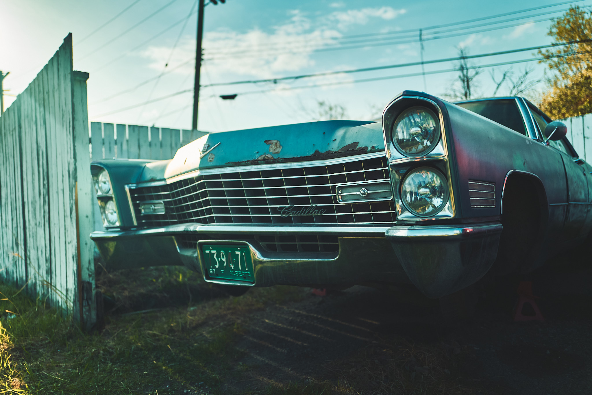 Close-up of a vintage Cadillac grille with Alberta plates behind a weathered fence