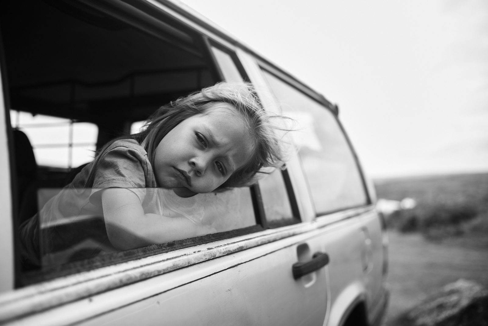 Child leaning out of car window on the prairies — black and white Leica photography