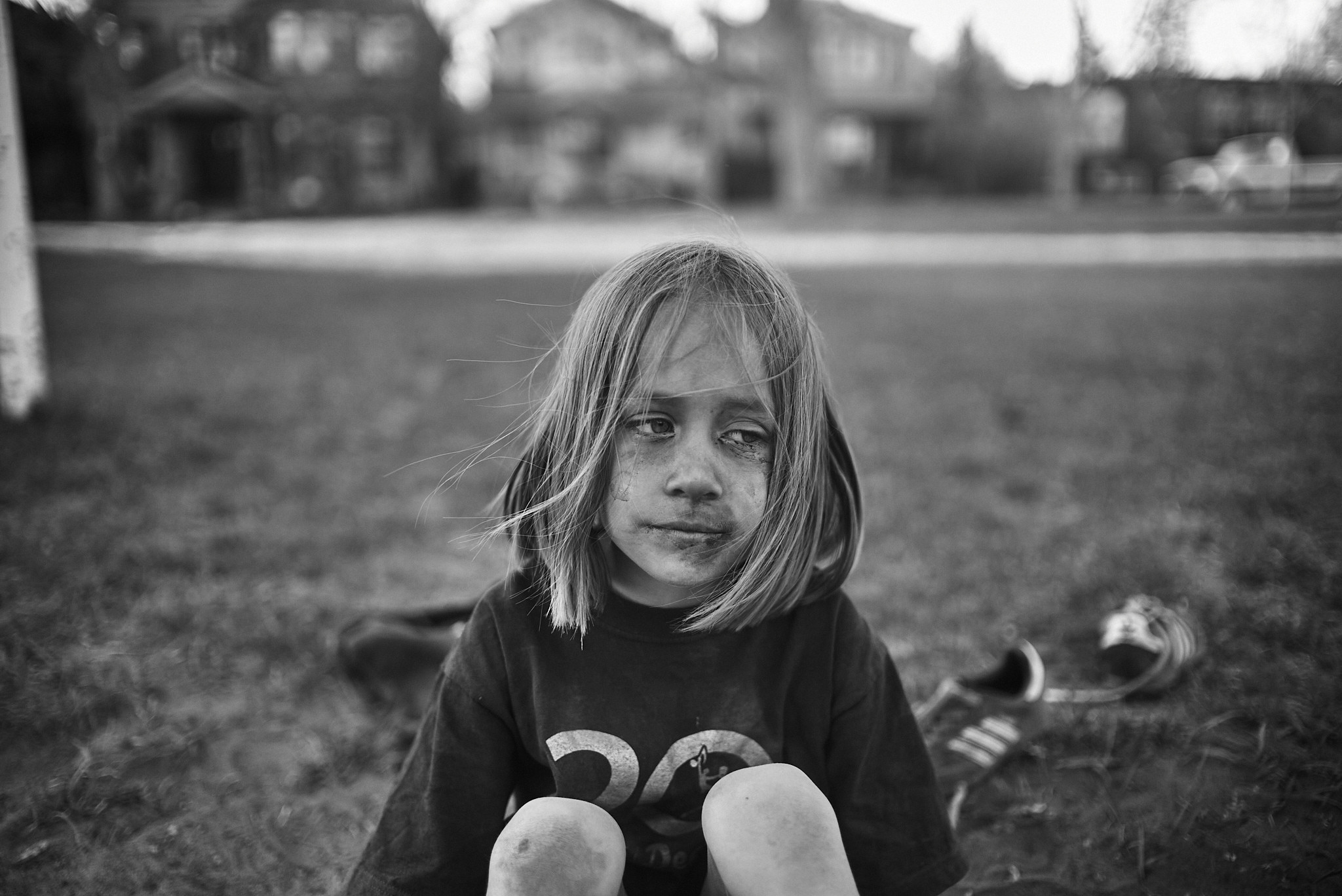 Child sitting on grass in neighbourhood — black and white portrait photography Calgary