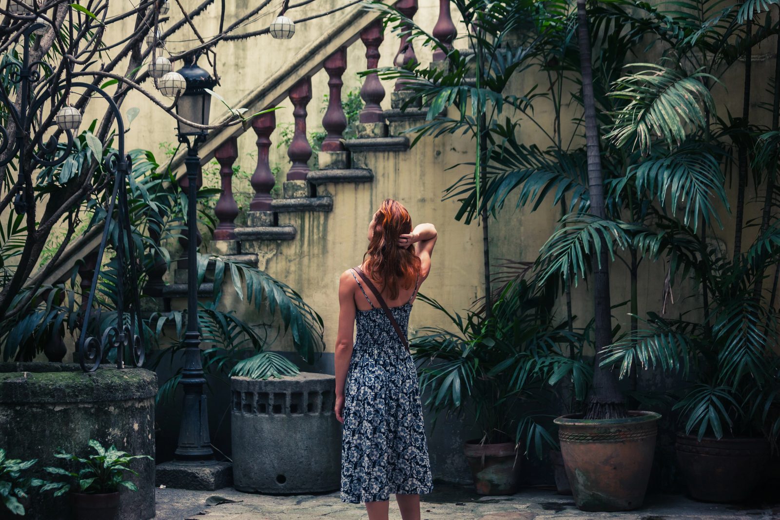 Woman by tropical staircase with lush plants — travel lifestyle photography