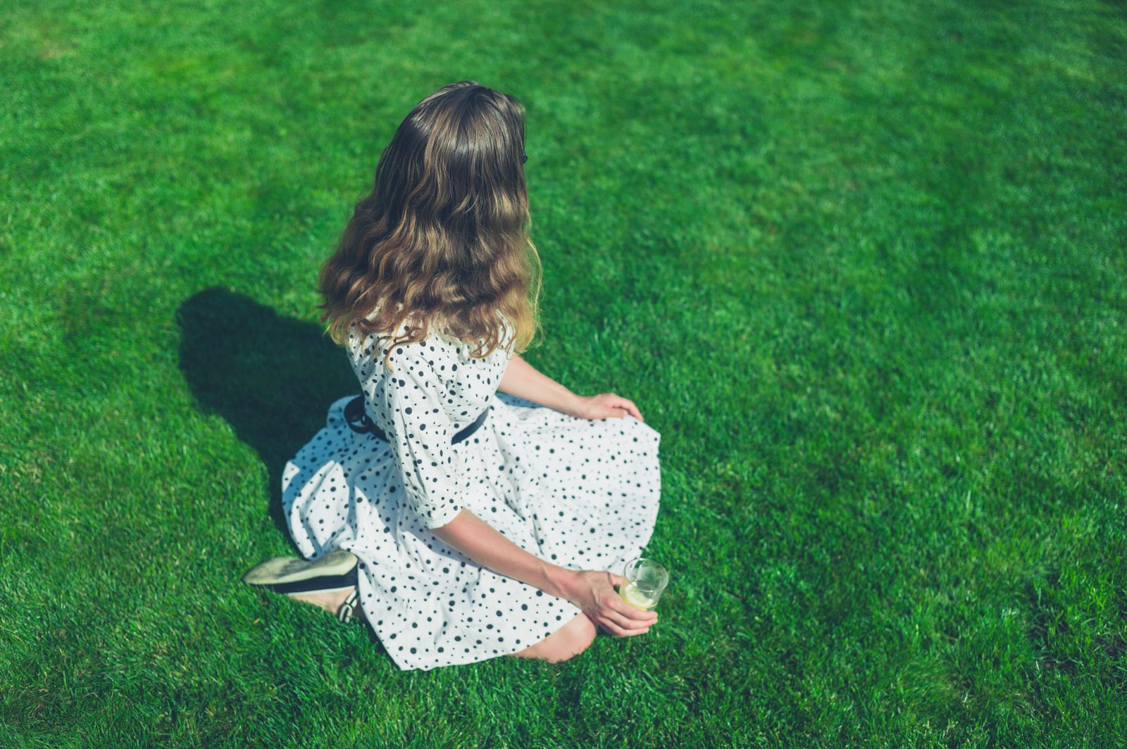Woman in dress sitting on lawn in summer — lifestyle editorial photography